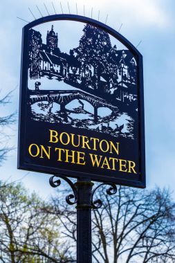 Bourton On Water şehir işareti bulutlu mavi gökyüzü karşı duruyor