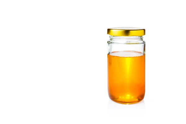 Miel dorada en frasco de vidrio con tapa sobre fondo blanco — Foto de Stock