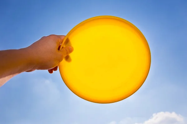 Männliche Hand hält gelbe Frisbee-Scheibe gegen blauen Himmel — Stockfoto