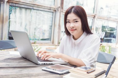 Genç mutlu Asyalı kadın onun dizüstü bilgisayar teknolojisi kullanarak 