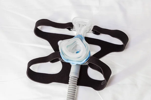 CPAP mask, connecting with strap and hose laying on a bed, for s — Stock Photo, Image