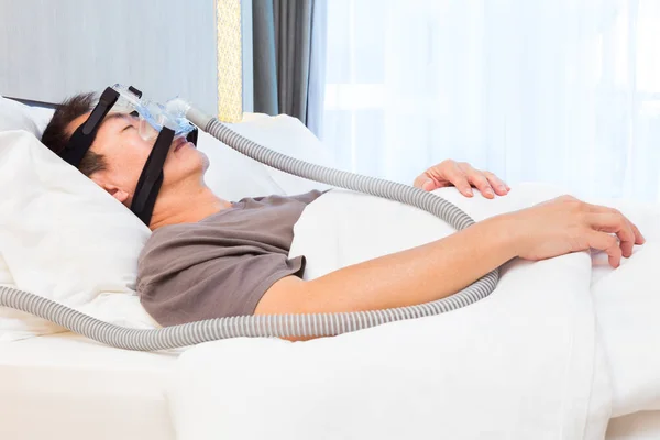 Orta yaş Asya adam uyku AI için bağlanma giyen Cpap maskesi