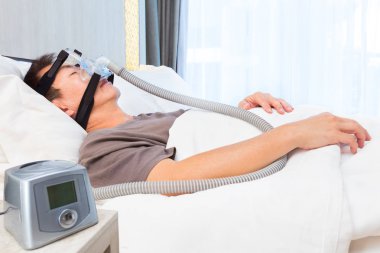 Orta yaş Asya adam uyku AI için bağlanma giyen Cpap maskesi