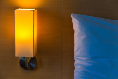 onun sıcak ışık ile başucu lamba beyaz yatağın yanında açık ve