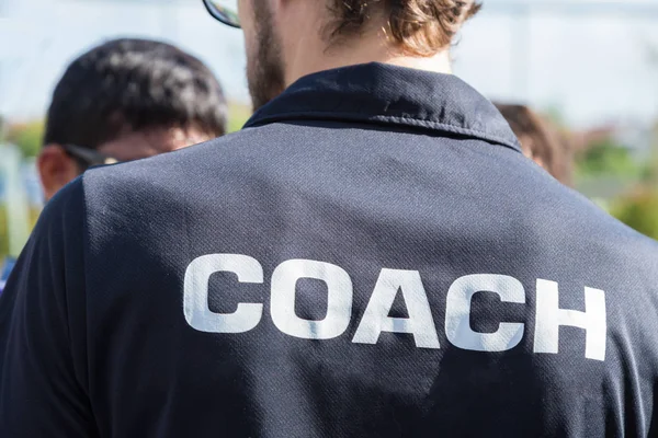 back of a sport coach's black shirt with the white Coach word wr