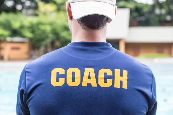 Back of a sport coach's blue shirt with the yellow Coach word wr — Stock Photo, Image