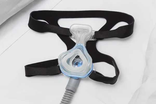 Maschera CPAP, cinturino per copricapo e tubo dell'aria sul letto bianco — Foto Stock