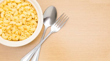 çatal ve kaşık ahşap masa ile pişmiş makarna makarna kase