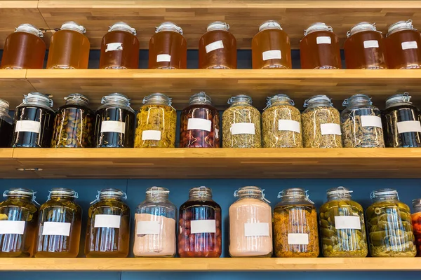 rows of preserved food in glass jars on wooded shelves