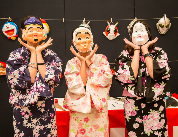 Asian tourists wearing Japanese funny folk character masks and t