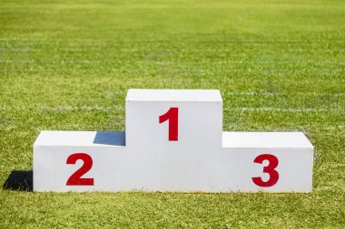Beyaz ahşap kazanan podyum yeşil çim spor sahası üzerinde yerleştirilen 