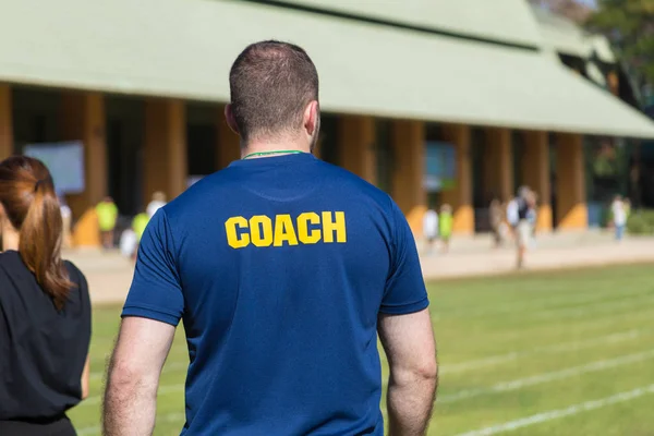 Parte posterior de un entrenador atleta masculino en camiseta azul profundo con gritos — Foto de Stock