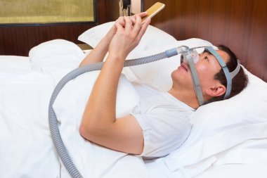 Orta yaş Asya adam yatağında CPAP maske ve USI döşeme