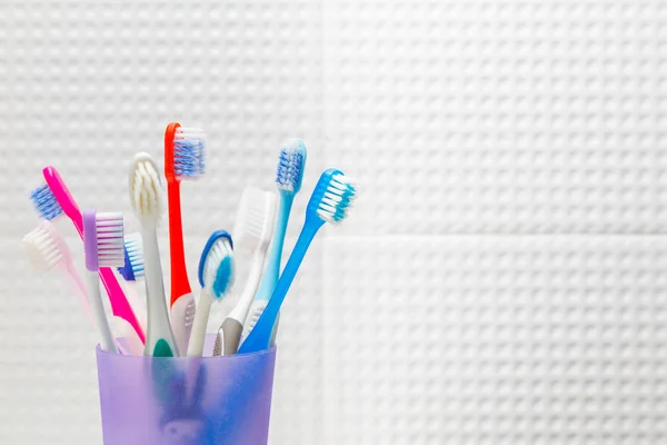 Cepillos de dientes usados en varios tamaños en un recipiente de plástico en whi — Foto de Stock