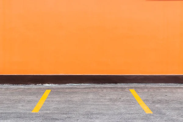 Orangefarbene Wand und Parkplatz mit bemalten gelben Trennwänden — Stockfoto