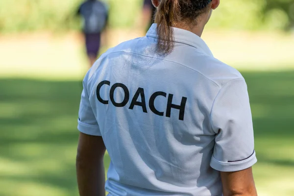 Rückansicht einer Sporttrainerin, die ihrem Team beim Wettkampf auf einem Sportplatz zusieht — Stockfoto