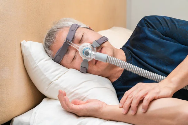 Orta yaşlı Asyalı adam uyurken Cpap başlık takıyor. — Stok fotoğraf