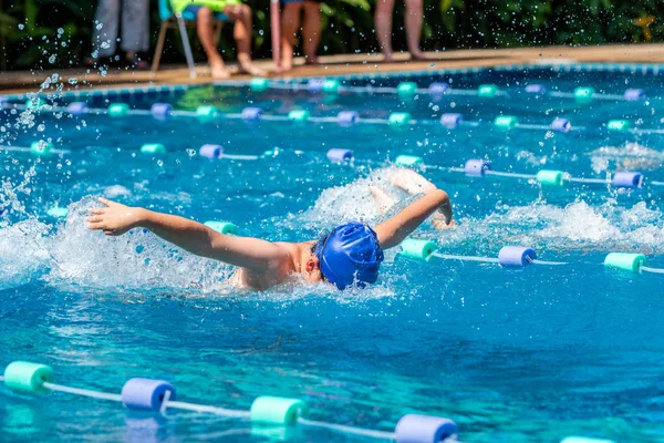 Young boy swimmer doing butterfly stroke at a pool on a bright sunny day — Stockfoto