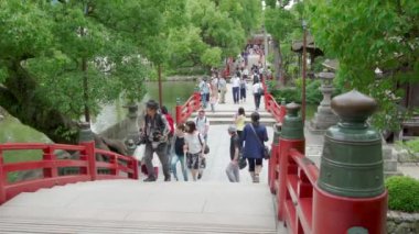 Dazaifu, Japonya - 10 Temmuz 2019 - Turistler ve yerli Japonhalkı 10 Temmuz 2019'da Dazaifu, Japonya'da ünlü Tenmangu Tapınağı'na giden güzel kırmızı köprüden geçiyor