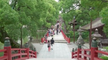 Dazaifu, Japonya - 10 Temmuz 2019 - Turistler ve yerli Japonhalkı 10 Temmuz 2019'da Dazaifu, Japonya'da ünlü Tenmangu Tapınağı'na giden güzel kırmızı köprüden geçiyor