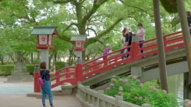 Dazaifu, Japonya - 10 Temmuz 2019 - Turistler ve yerli Japonhalkı 10 Temmuz 2019'da Dazaifu, Japonya'da ünlü Tenmangu Tapınağı'na giden güzel kırmızı köprüden geçiyor