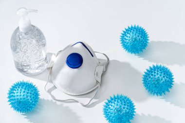 Antiseptik el jeli ve beyaz masada N95 maskesi ve kauçuk dikenli COVID-19 virüs oyuncak sağlık konsepti.