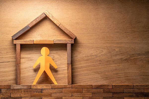 Paper cutout human figure in a wooden block made home on wood background, stay at home during COVID-19 virus outbreak concept with room for copy space