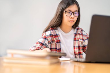 Corona virüsünün yayılması nedeniyle şehir tecridi sırasında evde çalışan ve okuyan genç Asyalı kız öğrenci