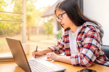 Corona virüsünün yayılması nedeniyle şehir tecridi sırasında evde çalışan ve okuyan genç Asyalı kız öğrenci