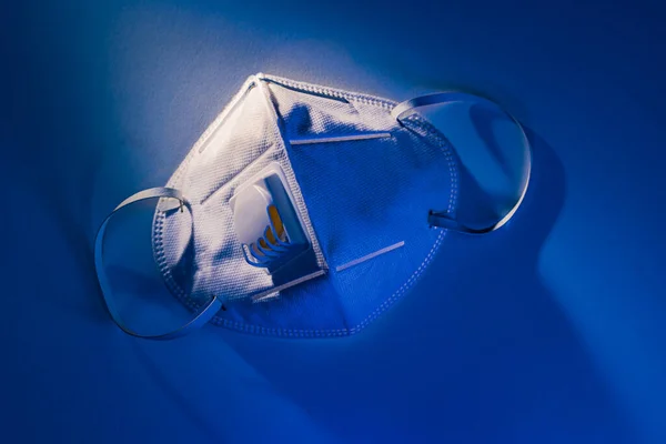Máscara N95 Sobre Mesa Blanca Con Dramático Efecto Iluminación Azul —  Fotos de Stock