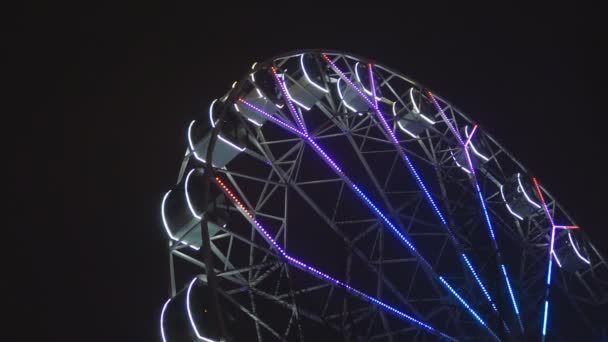 Roda gigante girando no parque de diversões sob o céu noturno escuro — Vídeo de Stock