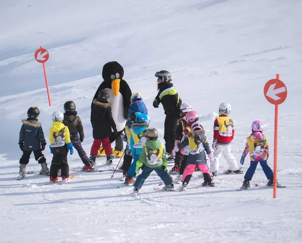 Skidlärare i pingvin kostym studerar barn. Skidorten i A — Stockfoto