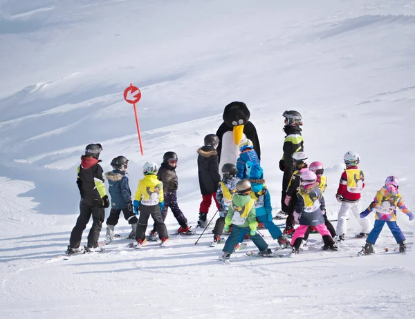 Лыжный инструктор в костюме пингвина изучает детей в лыжной школе . — стоковое фото