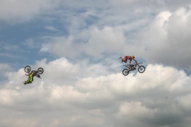 Freestyle Motocross trick of two motorcyclists on background of the blue cloud sky. Extreme sport. German-Stuntdays, Zerbst - 2017, Juli 08 clipart