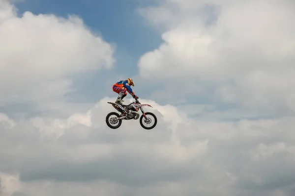 Freestyle Motocross αναβάτη διεξάγει ένα τέχνασμα με τη μοτοσικλέτα σε φόντο του ουρανού μπλε σύννεφο. Ακραίο άθλημα. Γερμανικά-Stuntdays, Τσέρμπστ - 2017, Juli 08 — Φωτογραφία Αρχείου