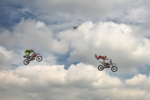 Freestyle-Motocross-Trick zweier Motorradfahrer vor dem Hintergrund des blauen Wolkenhimmels. Quadrocopter entfernt den Trick. deutsch-stuntdays, zerbst - 2017, juli 08 — Stockfoto