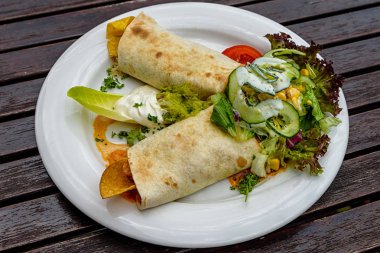 Burrito beyaz bir tabakta sebze ve sos ile. Otantik Meksika yemeği. Üstten Görünüm