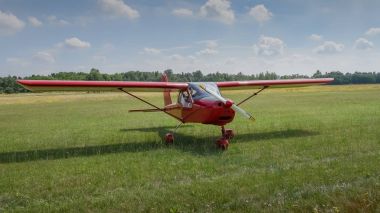 Hafif uçak. Işık kırmızı uçak iniş sonra Havaalanı çimenlerin üzerinde. Güneşli yaz günü ve mavi gökyüzü bulutlu
