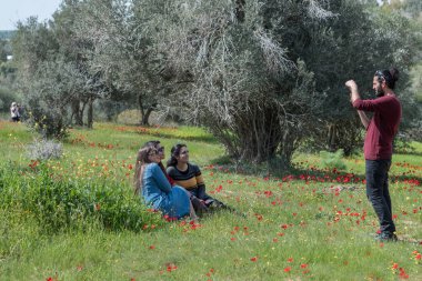 Kurkar Doğa Koruma Alanı, İsrail - 22.02.2019: Çayırdaki gençler, çiçeklere hayran olup fotoğraf çekiyorlar. İsrail 'de Kurkar Doğa Koruma Alanı