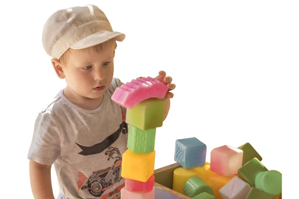 Little boy plays with colored cubes, builds a pyramid. Isolated — Stockfoto