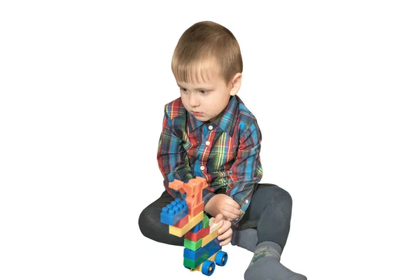 Little cute boy plays with colorful blocks at home, builds a car. Isolated — Stockfoto
