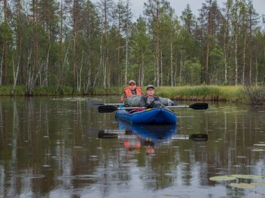 Baba ve oğul kanoda. Karelia 'da etkin bir tatil. Su turizmi. Ekoloji, kırılgan, el değmemiş, bozulmamış doğal alanları ziyaret etme. Şiddetli Karelya doğasının manzarası