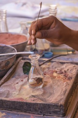 Ürdün, Petra 'daki renkli kumlardan hatıra alıyorum. Yerel halkın hayatı. Halk ve geleneksel sanatlar. Seyahat, dikey fotoğrafçılık