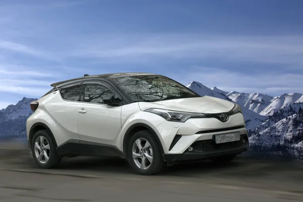 Toyota C-Hr beyaz araba dağlar ve mavi gökyüzü arka planı.