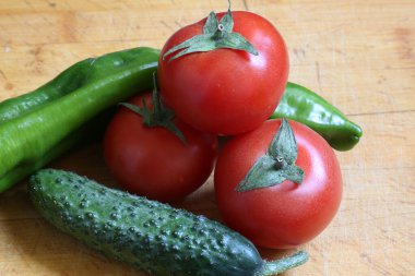 Sebzeler, kırmızı domatesler ve kesme tahtasında yeşil salatalık..