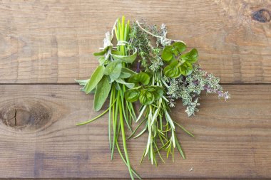 Ahşap arka planda taze toplanmış otlar.