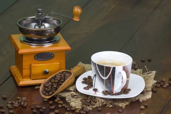 Чашка кофе, кофейные зерна и старая кофемолка на деревянной — стоковое фото