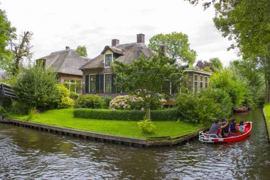 GIETHOORN, NETHERLANDS - 1 Ağustos 2017: Giethoorn 'daki bir kanalda tekne gezisinde bilinmeyen ziyaretçiler. Güzel evler ve bahçıvanlık şehri 