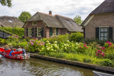 GIETHOORN, NETHERLANDS - 1 Ağustos 2017: Giethoorn 'daki bir kanalda tekne gezisinde bilinmeyen ziyaretçiler. Güzel evler ve bahçıvanlık şehri 