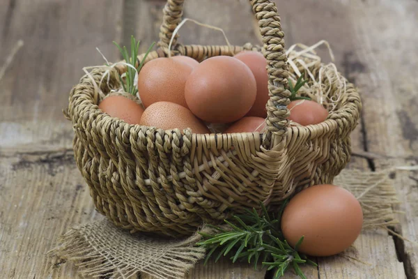 Huevos en una canasta sobre fondo de madera — Foto de Stock